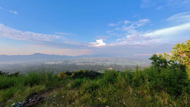 Mavi gökyüzü ve bulutlu dağ manzarası Arang Hill, Gorontalo, Endonezya