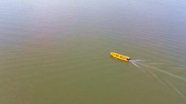 Suda yüzen sarı plastik bir teknenin havadan görüntüsü.