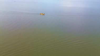Suda yüzen sarı plastik bir teknenin havadan görüntüsü.