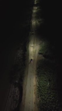 Geceleri yolda motosiklet süren bir adamın dikey videosu.