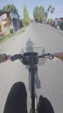 Güneşli bir yaz gününde kırsalda bisiklete binen bir adam. Doğal bir parkta bisiklet sürmek. POV.