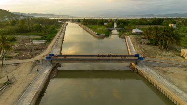 Endonezya 'da gün batımında nehrin üzerindeki köprünün hava görüntüsü.
