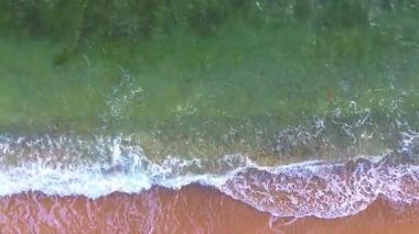 Turkuaz suyu ve dalgaları olan bir sahilin havadan görüntüsü.