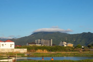Bulut oluşumlu dağ manzarası ve ön planda binalar