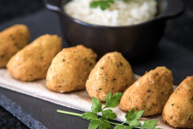 Bolinhos de bacalhau, Portekiz gastronomisiyle ünlüdür. Kızarmış hamur köftesi, morina köftesi, balık, tuzlu morina böreği, bacalao bunuelos. Siyah arka planda beyaz pirinçli morina balığı keki..