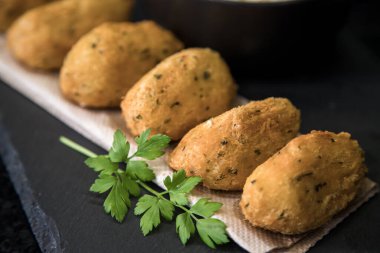 Bolinhos de bacalhau, Portekiz gastronomisiyle ünlüdür. Kızarmış hamur köftesi, morina köftesi, balık, tuzlu morina böreği, bacalao bunuelos. Koyu arkaplanda morina balığı keki.