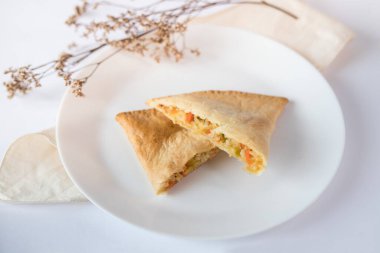 Vejetaryen börekleri bir tabakta ve beyaz masada üst üste dilimler halinde kesilmiş.