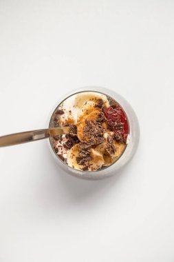 Chia seeds from the Salvia hispanica plant. Glass cup with hydrated seeds, natural yogurt, banana, strawberry jam, cinnamon powder and chocolate shavings. Image seen from above on white background. clipart