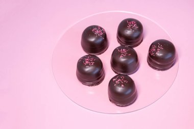 Altında çikolata ve vanilyalı gofretle kaplı pembe arka planda sünger şekeri..