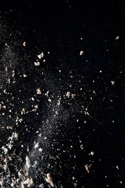 Un ve ekmek kırıntılarından oluşan koyu arkaplanda soyut bir resim. Kavramsal görüntü, uzaya ve evrene atıfta bulunma, bilinmeyen, ışık ve karanlık..