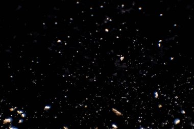 Un ve ekmek kırıntılarından oluşan koyu arkaplanda soyut bir resim. Kavramsal görüntü, uzaya ve evrene atıfta bulunma, bilinmeyen, ışık ve karanlık..