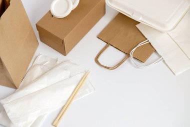 Beyaz arka plana yerleştirilmiş hazır gıdaların paketlenmesi ve taşınmasıyla ilgili kart ve kağıt unsurları. Gıda dağıtımının kavramsal görüntüsü, hazır yiyecek, sürdürülebilirlik ve geri dönüşüm.