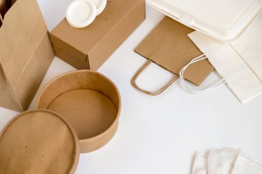 Beyaz arka plana yerleştirilmiş hazır gıdaların paketlenmesi ve taşınmasıyla ilgili kart ve kağıt unsurları. Gıda dağıtımının kavramsal görüntüsü, hazır yiyecek, sürdürülebilirlik ve geri dönüşüm.