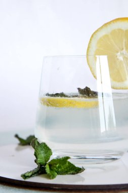 İçinde limonlu maden suyu ve beyaz arka planda naneli cam bardak. Limon ve nane bazlı ferahlatıcı içecek. Lezzetli ve sağlıklı limonata..