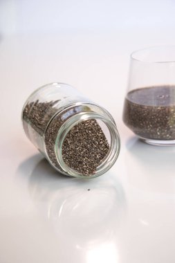 Pile of edible chia seeds from the Salvia hispanica plant. Very healthy functional food to use in various recipes. Cup containing the hydrated seeds. clipart