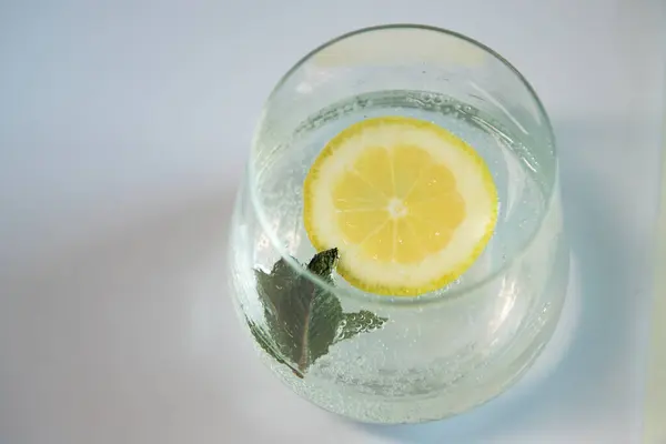 İçinde limonlu maden suyu ve beyaz arka planda naneli cam bardak. Limon ve nane bazlı ferahlatıcı içecek. Lezzetli ve sağlıklı limonata..
