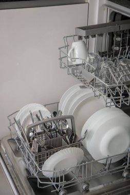 Bulaşık makinesi açık ve yıkanmış bulaşıkları kaldırmaya hazır. Günlük aktivitelerde su ve zaman tasarrufu kavramı.