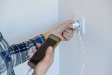 Akıllı telefon ve şarj aleti tutan birinin onu şarj etmek için yakın plan fotoğrafı. Yatay resim ve kopyalama alanı.