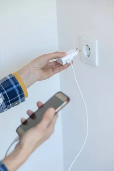 Akıllı telefon ve şarj cihazını yüklemek için birinin yakın plan görüntüsü. Dikey görüntü ve kopyalama alanı.