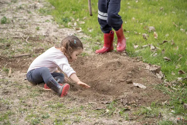 Boy and girl play together in great complicity, exploring nature, not afraid of getting dirty, just having fun. Happy childhood, friendship, sharing and learning concept.