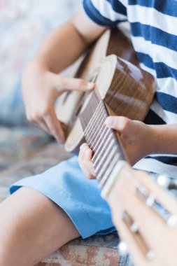 Beyaz çocuk küçük gitar ya da ukulele ile müzik akorları çalıyor ve yapıyor.