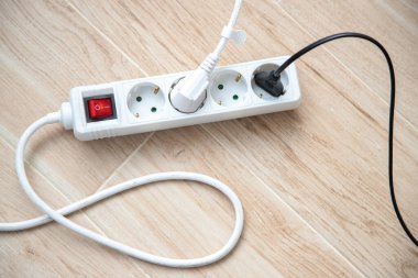 Electrical plug and multiple socket in use on the floor, Close up. clipart