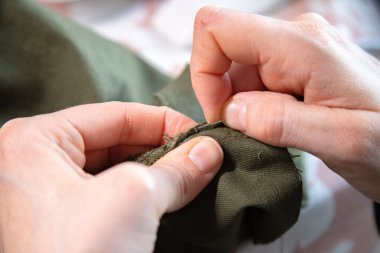 Evinde dikiş işi yapan beyaz bir kadının ellerinin ayrıntıları. İşlem ve uygulama. Ölçmek, kesmek ve dikmek bir pantolonu yeniden sarmak için..