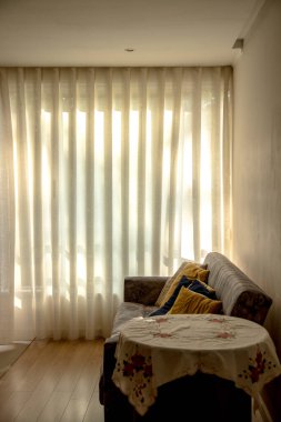 Güneşli Perde 'nin fotoğrafı ışığa karşı çekildi. Konforlu, rahat ve iç mekan ortamını hoş karşılıyor. Geçmişe odaklan. Dikey resim.