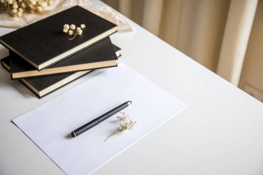 Beyaz masa, birkaç kitap, çarşaf ve kalem. Kavramsal görüntü, yaratıcılığın, bilginin ve boş zamanların temsili.