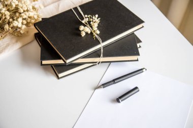 Beyaz masa, birkaç kitap, çarşaf ve kalem. Kavramsal görüntü, yaratıcılığın, bilginin ve boş zamanların temsili.