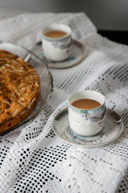 Kahvaltı ya da kahve molası, ev yapımı bademli kek ile birlikte, kırsal, samimi ve samimi bir atmosferde. Süslü bir masada hazırlanmış fincanlarla servis edilen kahve..