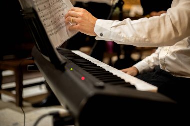 İç kilise ortamında klavyede müzik çalan klasik giysili beyaz bir adamın elleri. Kapat.