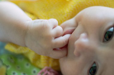 Sevgi dolu bebek parmaklarını ağzına sokup gülümseyen kameraya bakıyor. Duyusal deneyimle dünyayı tanıma kavramı.