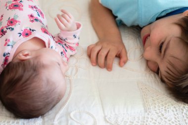 Ağabeyi ailesinin yatağında yeni doğan kız kardeşine bakıyor. Kardeşler, şefkat ve sevgi arasındaki eşsiz anlar..