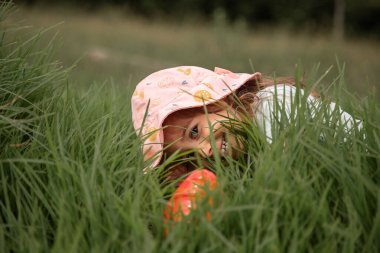 Mutlu çocukluk kavramı, etrafındaki dünyayı keşfetmek. Gün boyunca parkta saklambaç oynayan ve gülümseyen bir kız..