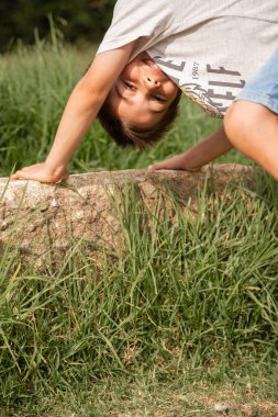 Sevecen ve komik çocuk gün boyunca çimenli bir parkta saklambaç oynayıp motor becerileri geliştiriyor. Mutlu çocukluk kavramı, etrafındaki dünyayı keşfetmek..