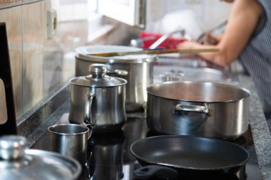 Mutfakta tavayla yemek pişiren bir kadın. Ev işi kavramı, evde yemek yapmak..