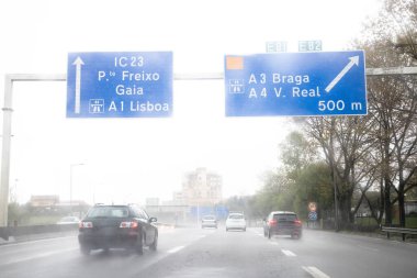 İç çevre yolunun görüntüsü, VCI, Porto, Portekiz. Kötü hava koşulları ve sağanak yağışlı bir günde yerel trafik. Bilgi paneli, yönler.