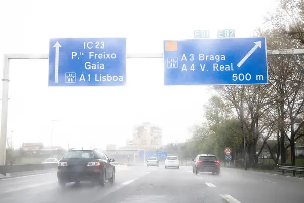 İç çevre yolunun görüntüsü, VCI, Porto, Portekiz. Kötü hava koşulları ve sağanak yağışlı bir günde yerel trafik. Bilgi paneli, yönler.