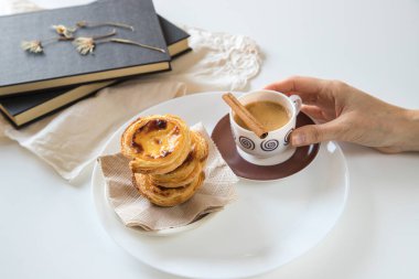 Pasteis de nata, Portekiz mutfağının geleneksel tatlısı. Küçük, çıtır çıtır börekler ve yumurtadan krema. Sık sık kahveyi tattı ve eşlik etti. Elinde kahve tutan kişi..
