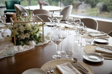 Özel bir etkinlik için zarif bir yemek masası, güzel bir çiçek süsü, şarap kadehleri, ve ince düzenlenmiş çatal bıçaklar, sofistike ve misafirperver bir atmosfer yaratıyor..