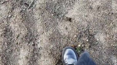 Parlak, su geçirmez siyah botlar giyen biri kaba toprak zeminde ve paltoda yürüyor. Aksiyon yürüyüşü macerası..