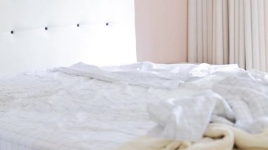 Bir insan, yatağı yapmak için yatağı düzenler. Parlak, minimalist bir yatak odasında temiz ve düzenli bir yatak odası yaratır..