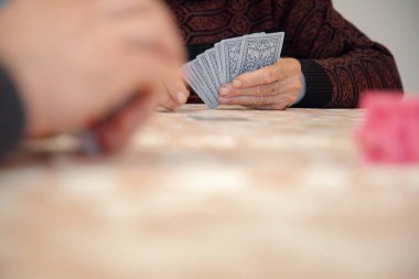 Bir grup insan bir masanın etrafında toplanır, aile veya arkadaşlarla gündelik bir oyun oynar, sosyal etkileşimi, arkadaşlığı ve bilişsel bağlılığı teşvik ederler..