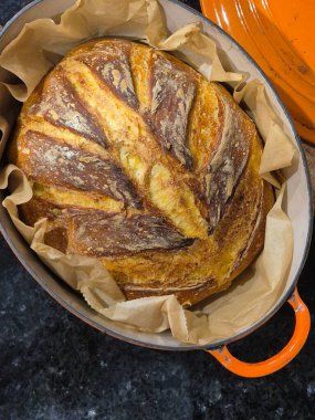 A freshly baked artisanal pumpkin bread with the main ingredient in an orange cast iron pan lined with parchment paper. clipart