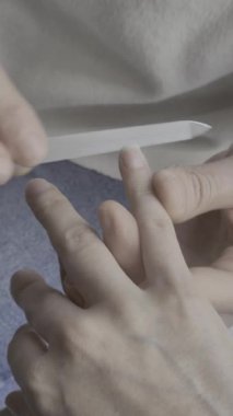 Evde biri diğerine tırnaklarını metal bir tırnak törpüsüyle törpülemesine yardım ediyor. Bu yakın çekim kişisel bakım, hijyen ve detaylara basit ama gerekli bir bakım rutinini vurguluyor..
