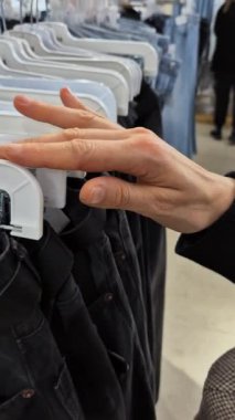Bir müşteri bu ürünlerin seri üretimini göstermek için hızlı moda mağazasında kot pantolonlara göz atar. Bu video, perakende ortamda modern tüketici alışkanlıklarını ve moda seçimlerini yakalıyor..