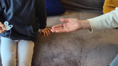 Bir çocuk hasarlı bir emziği bir yetişkine verir, bu da rahatlatıcı bir nesneye duygusal bir veda demektir. Sembolik bir büyüme, geçiş ve içten bir videoda yakalanmasına izin verme anı..