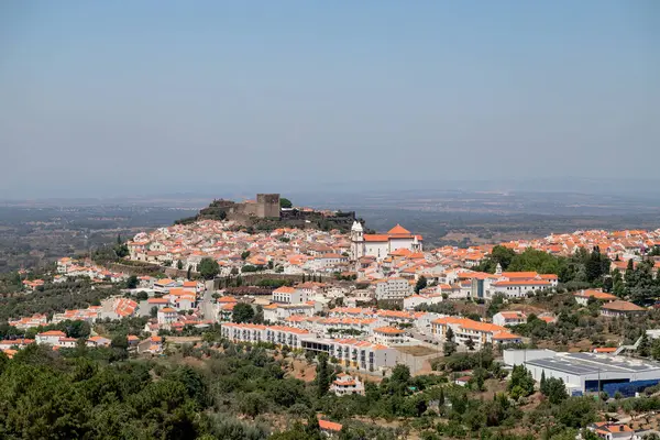 Portekiz 'in Alentejo kentindeki tarihi bir köy olan Castelo de Vide' nin panoramik manzarası, ortaçağ şatosu ve kırmızı çatılı beyaz evleri aydınlatarak, manzaralı bir yaz günü çekildi..