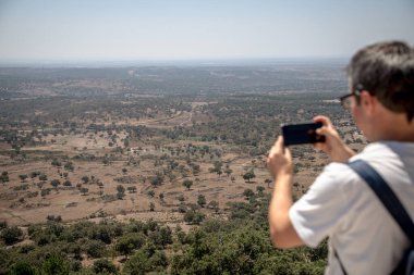 Bir turist, güneşli bir yaz günü Fonte dos Carvoeiros manzarasından Carreiras, Portalegre, Alentejo, Portekiz 'in panoramik manzarasını yakalar ve kırsal manzaraya hayran kalır..